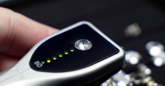 Close-up of diamond tester with green lights and sparkling stones