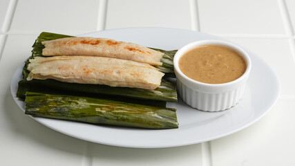 Otak-otak Tengiri, made from fish and flour covered with banana leaf. Served with peanut sauce. Indonesian food