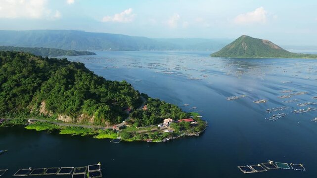 Expansive daytime aerial from Binintiang Malaki Western Viewpoint capturing Taal Volcano, mountains, and square ocean fishpond networks with small boats.