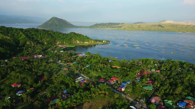 Daytime aerial footage from Binintiang Malaki Western Viewpoint showing Taal Volcano, mountain ridges, and square ocean fishponds with tiny boats in one scenic frame.