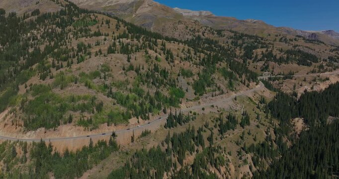 Remote alpine highway winding by dense forest and rolling San Juan terrain, Million Dollay Highway Colorado USA