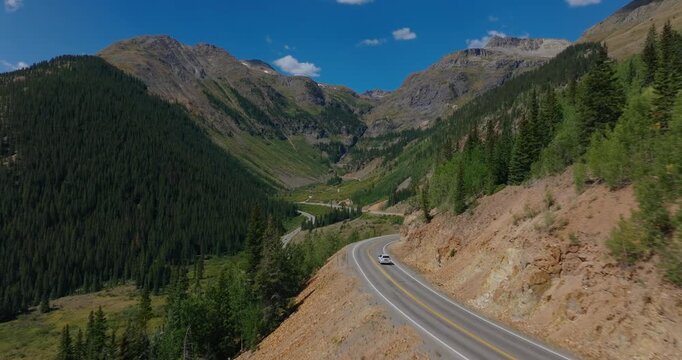 Winding alpine highway cutting across steep green slopes in the Colorado San Juans, Million Dollay Highway Colorado USA