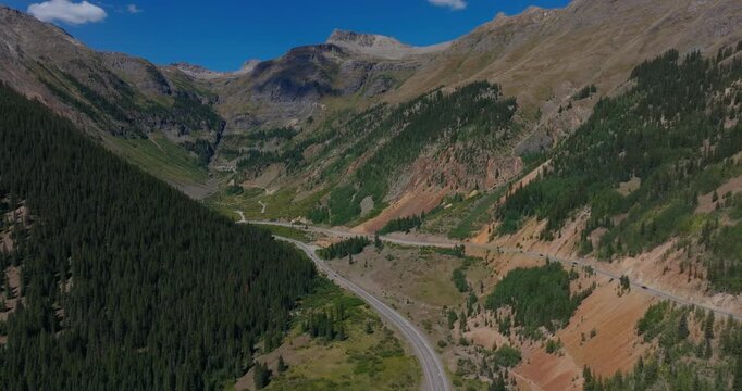 Dramatic mountain roadway stretching across green Colorado hills and rugged ridgelines, Million Dollay Highway Colorado USA