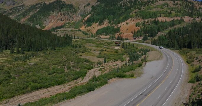 Winding mountain road cutting across rugged Colorado terrain under clear summer skies, Million Dollay Highway Colorado USA