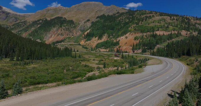 High mountain highway curves by green San Juan slopes with dramatic alpine, Million Dollay Highway Colorado USA