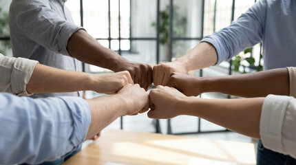 Teamwork unity diversity collaboration fist bump success business partners expressing community. Diverse multi-ethnic professional group celebrating project completion in office.