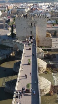 Revealing the medieval Torre de Calahorra, its town museum, and the Roman Bridge over the Guadalquivir River in C&oacute;rdoba, Spain. Vertical aerial.