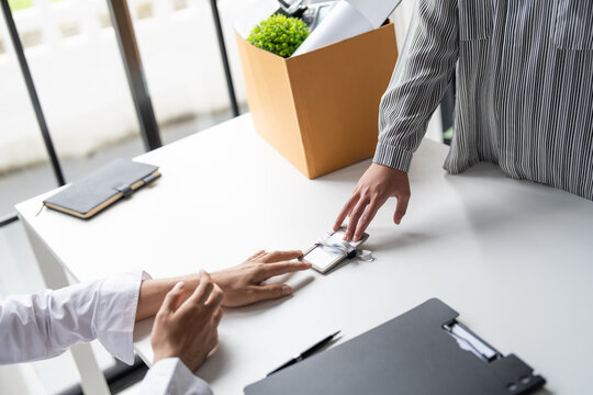Business woman sending resignation letter to boss and Holding Stuff Resign Depress or carrying cardboard box by desk in office.