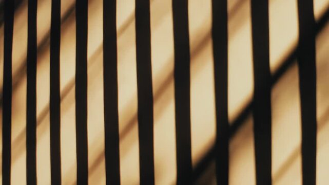 Shadow stripes from a window or fence creating a dynamic, abstract geometric pattern on a light colored surface, highlighting interplay of light and dark