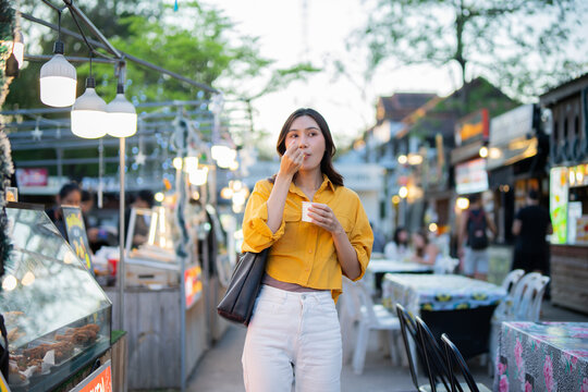 Asian women enjoy delicious street food at night markets, smiling throughout their vacation, exploring the city's culture, vibrant lights, and fun-filled adventures.