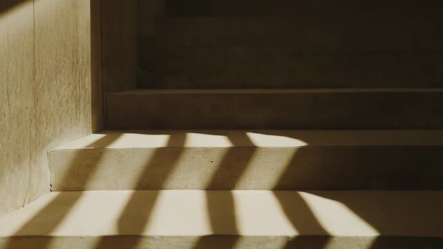 Concrete stairway bathed in warm, natural light creating a strong pattern of parallel shadows and highlighting the texture of the minimalist architecture