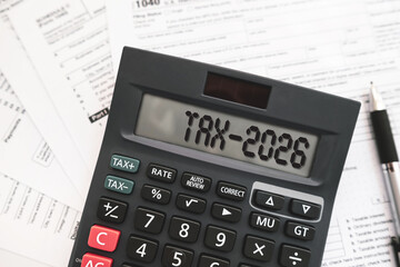 Calculator displaying the word &ldquo;TAX 2026&rdquo; on official tax forms. Ideal for topics related to income tax, tax calculation for filing taxes