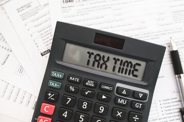 Calculator displaying the word &ldquo;TAX TIME&rdquo; on official tax forms. Ideal for topics related to income tax, tax calculation for filing taxes