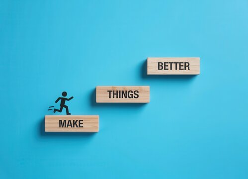 Small wooden blocks with the words make things better stacked like stairs with a small black silhouette of a running person on a blue background