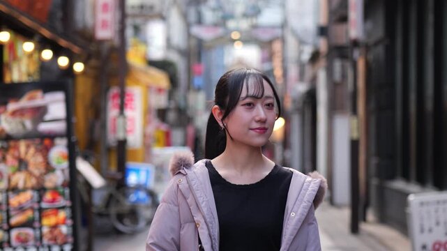 東京のレトロな商店街を歩く若い女性のトラッキングショット