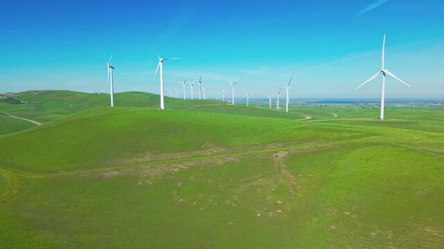 The drone glides over Altamont Pass wind farms, revealing sweeping hills dotted with turbines that generate clean energy against a wide California sky.