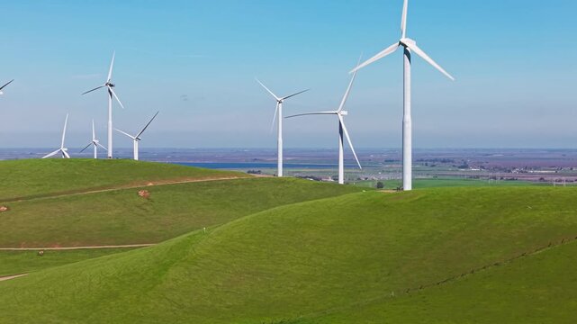 Elevated views highlight the scale of the wind farms near Altamont Pass, with long lines of turbines stretching across the terrain in rhythmic motion. Ascending drone shot filmed in 4K.