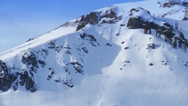 Downhill skiing and snowboarding on wide open mountain slopes at Palisades Tahoe, California USA. Winter alpine scenery with active riders descending through snow.