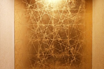 Decorative wall covering with a gold metallic texture and abstract line patterns.