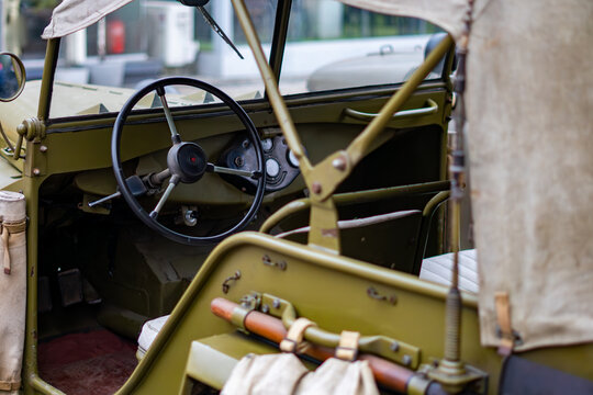 Interior of a vintage military off-road vehicle featuring the steering wheel, dashboard, and canvas top of a classic GAZ-67, historical military reenactment and army vehicle restoration.