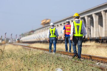 Rail maintenance team conducting safety check on railway tracks, Railway engineers walking along track during infrastructure inspection, Transportation workers inspecting freight train and rail line
