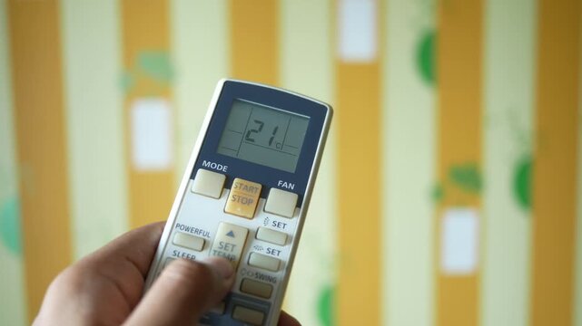 Close up of hand adjusting air conditioner remote temperature settings
