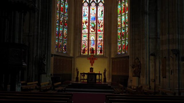 Cathedral altar framed by stained glass windows and gothic arches in low light 