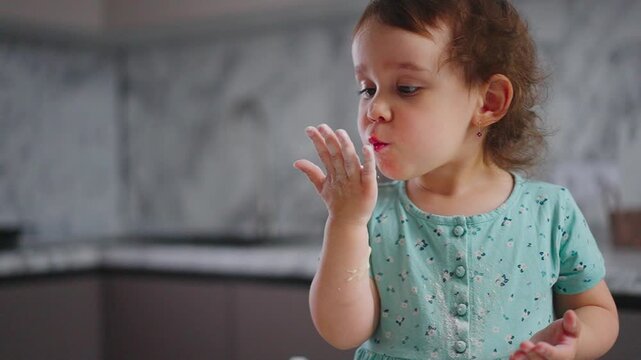 A Young Child Curiously Examines the Texture of Powder on Their Hand While Experiencing a Playful Moment in the Kitchen, Capturing Innocence and Wonder