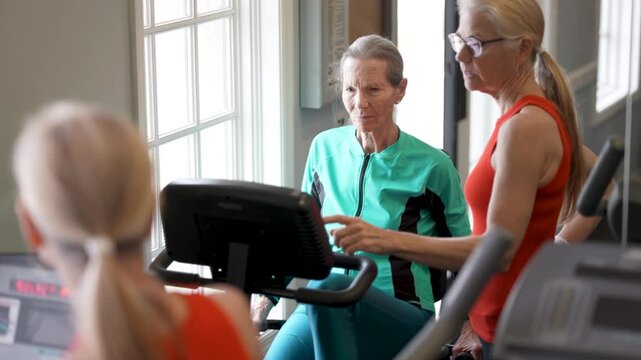 Elderly woman exercises in gym while trainer provides help and guidance for better workout routine and fitness improvement