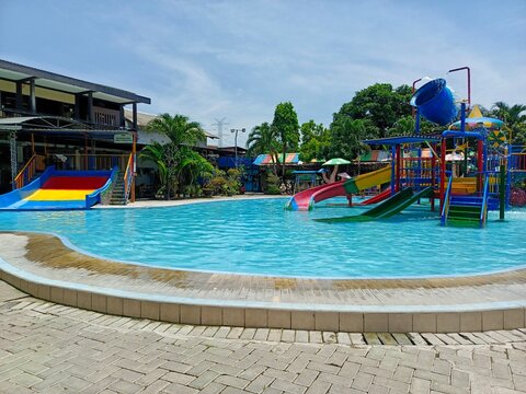 Colorful kids water park with slides and splash pool at a tropical resort under a clear blue sky