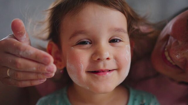 Joyful Moments: A Loving Interaction Between a Parent and Their Child as They Playfully Apply Cream, Showcasing Pure Happiness and Bonding in an Intimate Setting