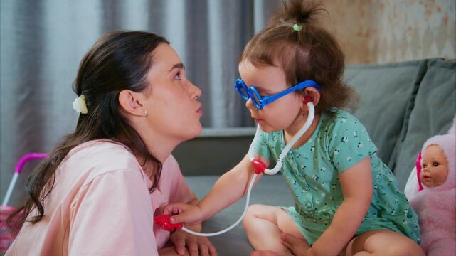 A Child's Playful Encounter: A Young Girl in Toy Glasses Pretends to Be a Doctor While Engaging with Her Mother in a Loving Living Room Atmosphere