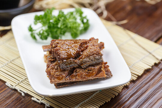 Flavored braised ribbonfish served on a rounded, elongated porcelain plate