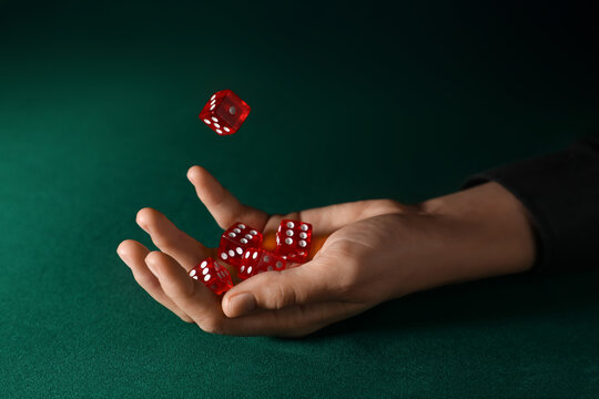 Male hand with red game dices on green background