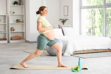 Obraz premium Sporty pregnant woman training in bedroom
