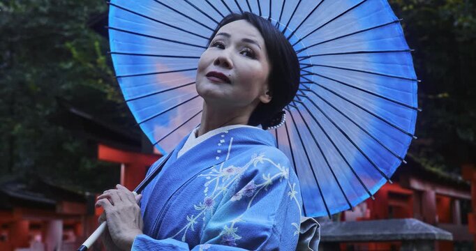 Happy Japanese woman in kimono holding umbrella and staring at sky - medium slow motion shot