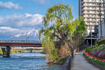 Buildings and promenade and riverside walkway at Katakami riverflowing through the middle of Morioka city, Iwate Cityscape  with Iwate Mount Background scene in Morioka,  Iwate, Japan