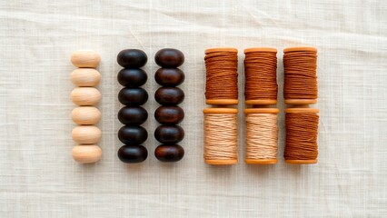 Collection of wooden beads and spools of thread on a light fabric background