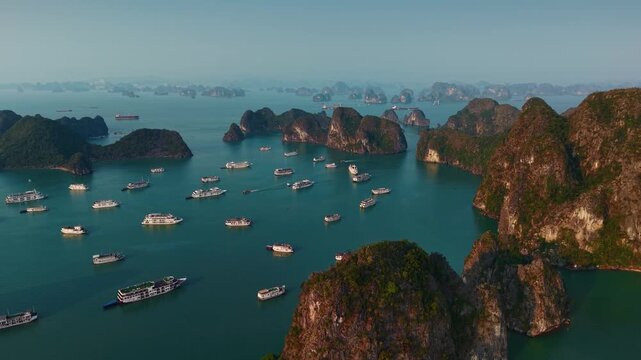 Scenic sunset over Halong bay with tour cruise boats and limestone islands.