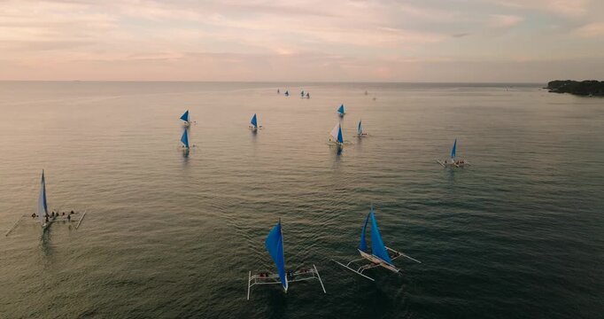 Sunset activity in Boracay. Paraw sailing boats over the sea. Philippines.