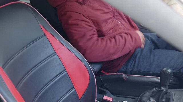 The driver releases the handbrake and puts on his seatbelt.