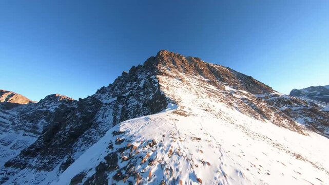 Breathtaking Aerial View of Snow Covered Mountain Sumit Under Clear Blue Sky