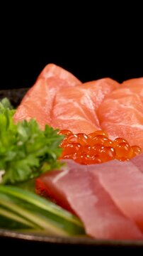 Vertical Close-Up of Rotating Fresh Sashimi Platter on Black Background