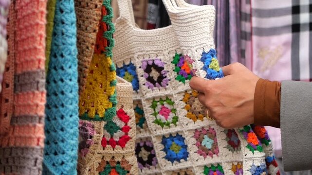 Woman hand choosing colorful handmade crochet bag in local street market bazaar