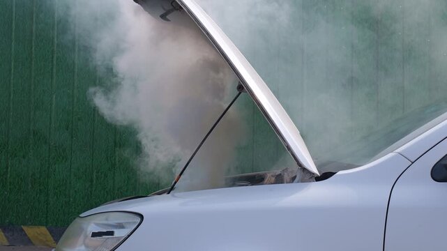 The car catches fire and smokes white; the car driver calls for help.