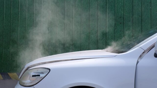 The car catches fire and smokes white; the car driver calls for help.