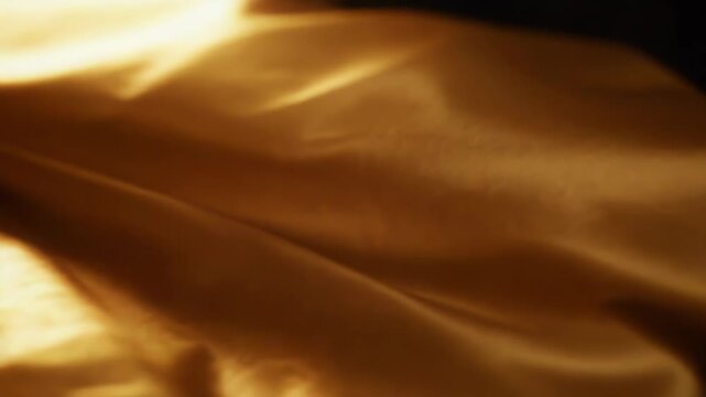 Crumpled shiny gold metallic foil surface forming an abstract textured background, offering a rich and opulent feel with its reflective creases and vibrant yellow color