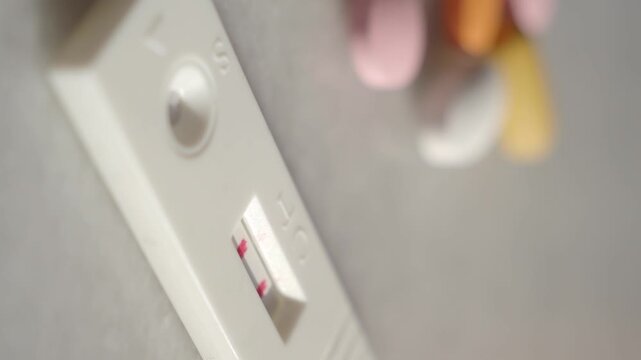 Positive pregnancy test results with colorful pills on background showing medical concept of family planning