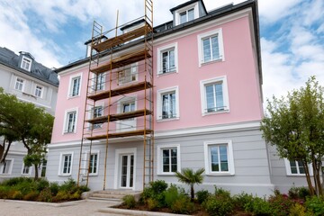 Obraz premium Pink building facade undergoing renovation with scaffolding