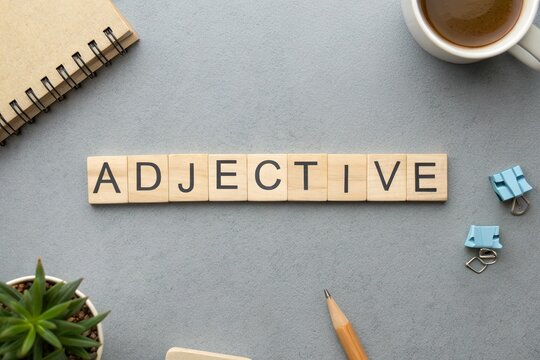 Creative workspace featuring wooden letter tiles spelling 'ADJECTIVE' with coffee and stationery